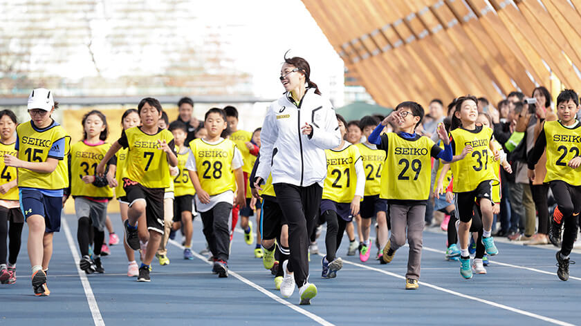 ウォーミングアップする子供たちと福島千里選手 写真