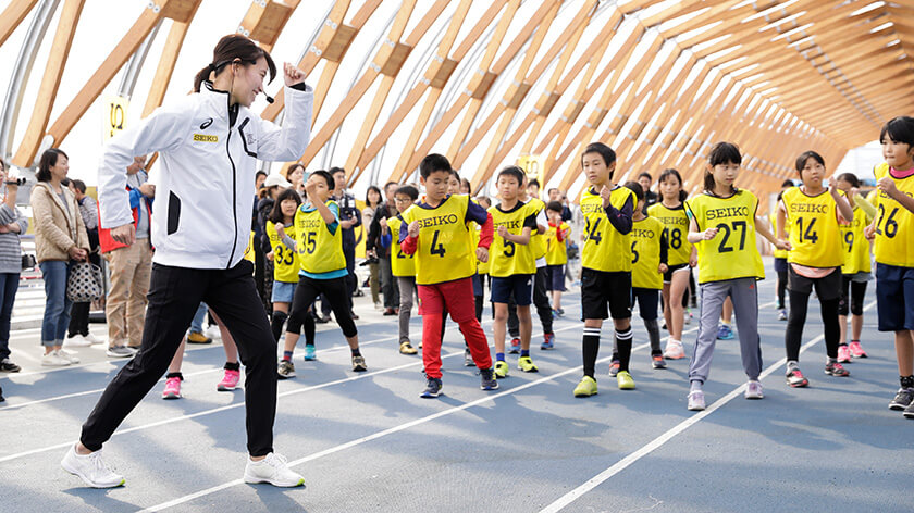 ウォーミングアップする子供たちと福島千里選手 写真