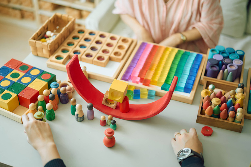 虹色の積み木の赤いパーツを逆さにして積み木を乗せていく遊びの様子