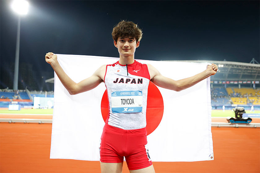 ユニバの舞台で豊田選手が日本国旗を両手で持っている写真