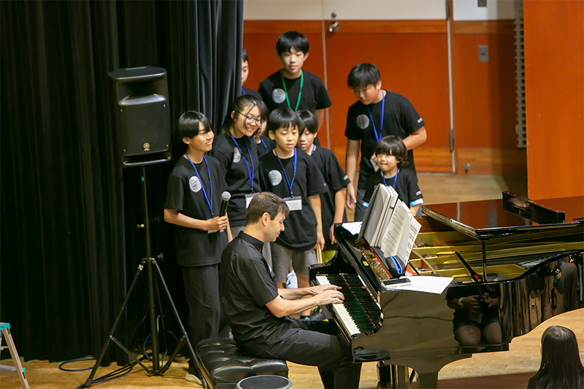 ピアノを演奏するダン・ニマーとピアノを囲む生徒たち