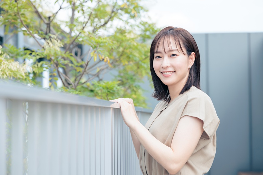 手すりに手を添えて笑顔を見せる石川さん