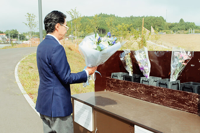 防災庁舎遺構の前で献花する実行委員長 服部